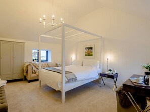 Ein Schlafzimmer mit einem Himmelbett, einem Kleiderschrank, einem Schreibtisch mit Lampe und einem Fenster mit Aussicht.