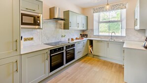 Een moderne keuken met een magnetron, oven en een dubbele spoelbak.