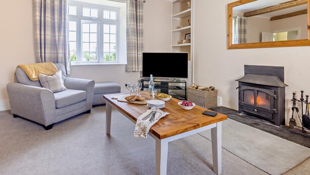 Een woonkamer met een bank, een houten tafel met een televisie, een open haard en een grote spiegel.