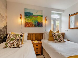 A bedroom with two beds, a wooden headboard, a nightstand, a wall-mounted painting, and a window with a view. - 2 Bed in Barnstaple (oc-94038) (Bishop's Tawton)