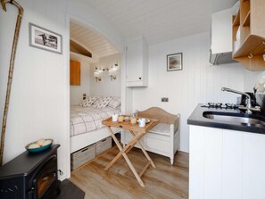 Eine kleine Küche mit Herd, Esstisch und einem Bett in der Ecke.