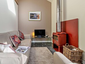 A living room with a sofa, a television, a red wood-burning stove, and a framed picture on the wall. - 2 Bed in Aberdyfi (oc-dy031) (Aberdovey)