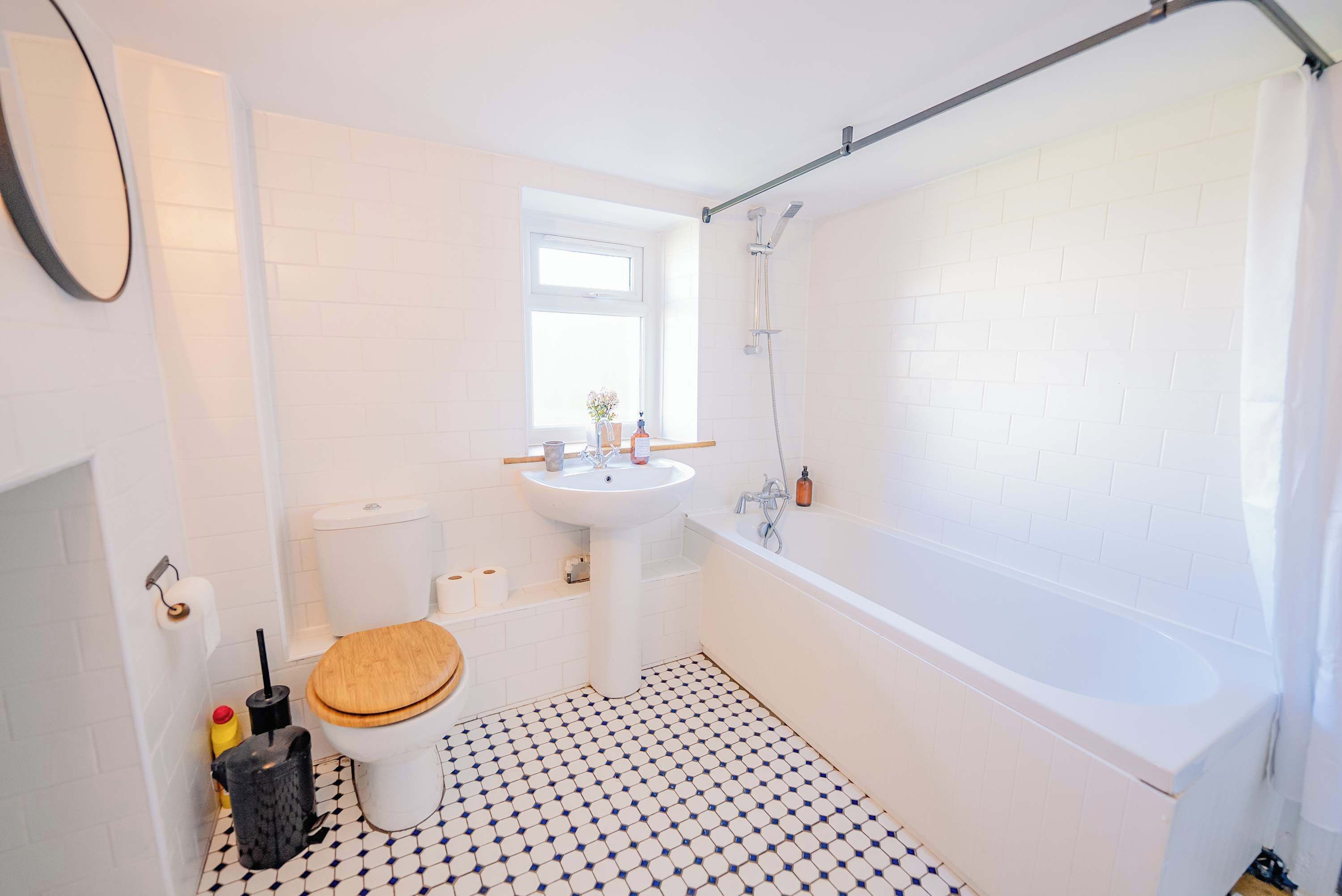 A bathroom with a toilet, sink, bathtub, and a window.
