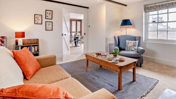 A living room with a sofa, a coffee table, a lamp, and a view of a dining area through an open door. - 1 Bed in Sherborne (oc-94306) (Chetnole)