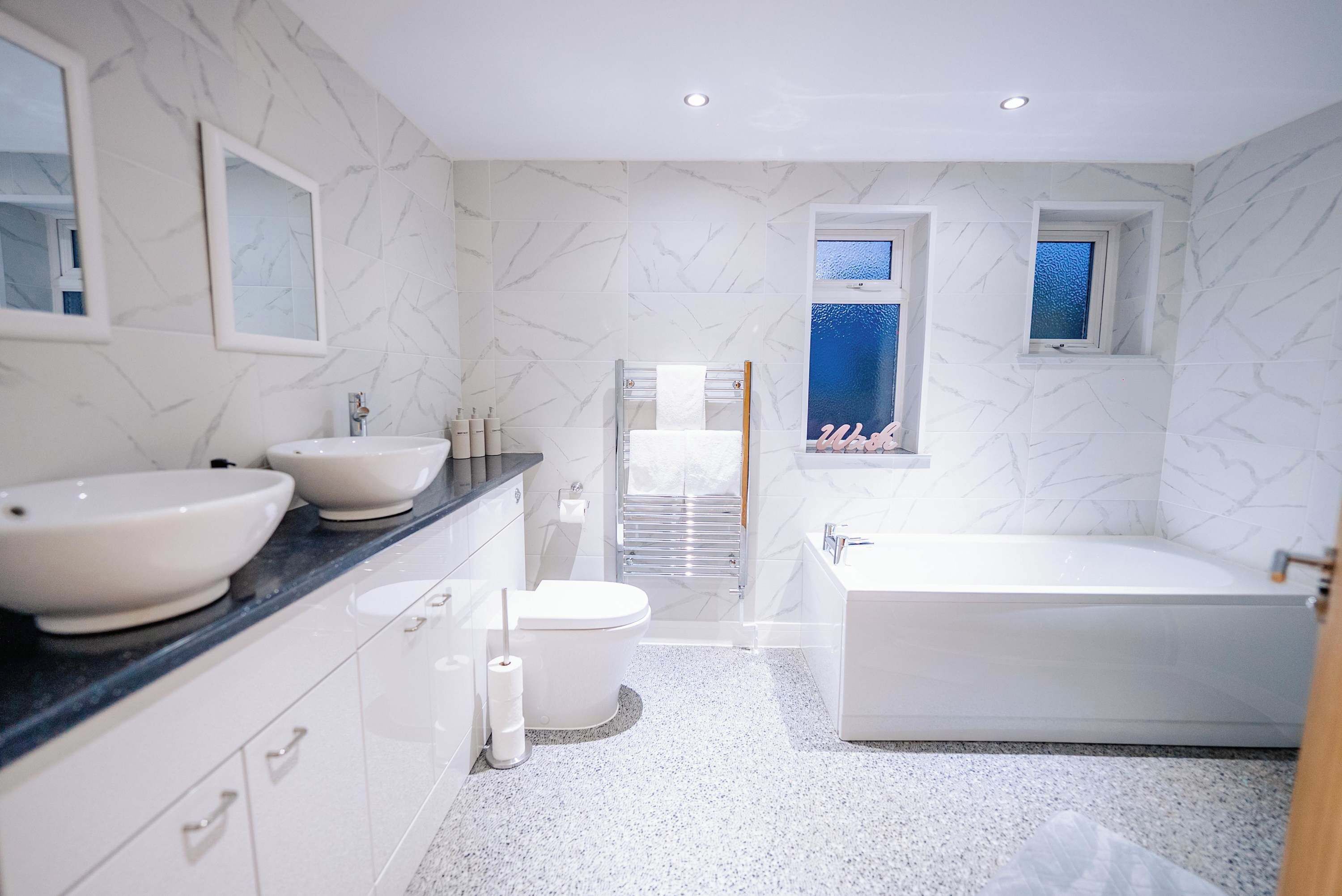 Une salle de bain moderne avec deux lavabos, des toilettes, une baignoire et une douche.