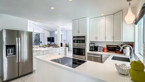 A modern kitchen with stainless steel appliances, a central island, and white cabinetry. - Stunning Mountain Views, Mid-Century Modern Private Home W/ Pool & Spa (Palm Springs)