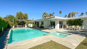 A modern house with a swimming pool, outdoor seating, and a pergola.