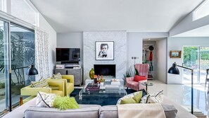 A modern living room with a sofa, armchairs, a coffee table, a fireplace, and a television.