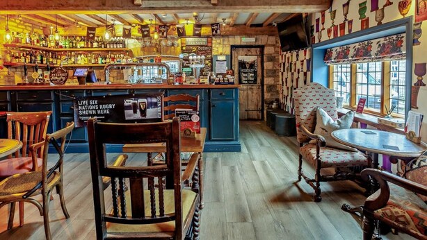 A bar with wooden beams, a variety of bottles, and a sign for live rugby. - 3 Bed in Langport (oc-94302) (Curry Rivel)
