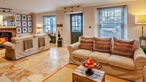 A living room with a fireplace, two sofas, a coffee table with fruit, and framed pictures on the wall. - 3 Bed in Langport (oc-94302) (Curry Rivel)