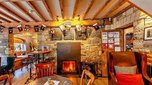 A cozy pub with a stone wall, wooden beams, a fireplace, and a bar area. - 3 Bed in Langport (oc-94302) (Curry Rivel)