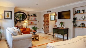 A living room with a sofa, a coffee table, a TV, and a brick wall. - 3 Bed in Langport (oc-94302) (Curry Rivel)