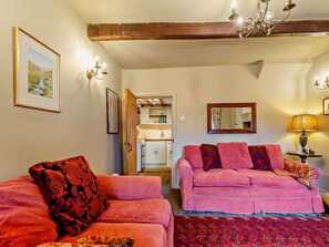 A cozy living room with two sofas, a chandelier, a mirror, and a kitchen visible through an open door. - 2 Bed in Skipton (oc-94337) (Hebden)