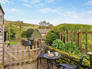 A rustic outdoor seating area with a table and chairs, a wooden fence, and a hedge. - 2 Bed in Skipton (oc-94337) (Hebden)