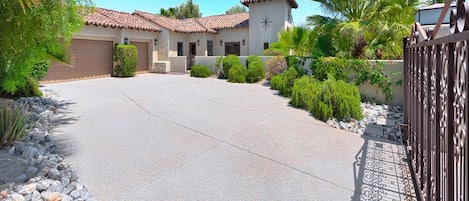 Propiedad residencial con entrada pavimentada, acceso con portón y edificio con techo de tejas y paredes de estuco.