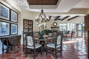A dining area with a round table, chairs, a chandelier, and patterned wall art. - Outdoor Shower, Swim-Up Wetbar, Hot Tub, Putting Area, Firepit, EV Charger (Palm Springs)