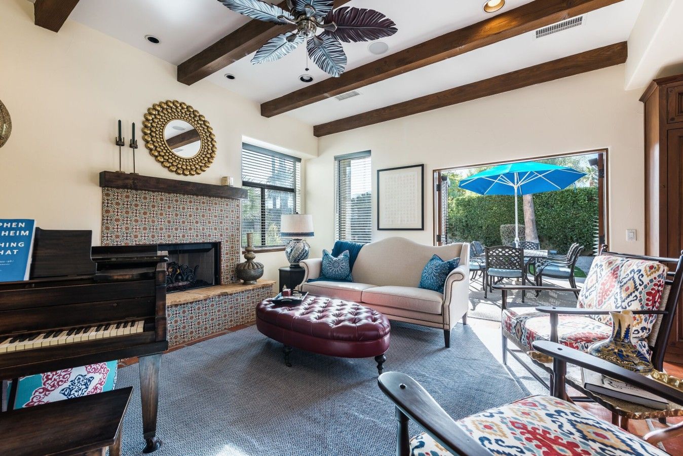 A living room with a fireplace, a piano, a sofa, and a dining area with outdoor seating.