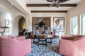 A living room with a sofa set, a coffee table, a decorative wall piece, and a large window. - Outdoor Shower, Swim-Up Wetbar, Hot Tub, Putting Area, Firepit, EV Charger (Palm Springs)