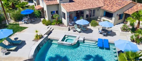 Propiedad residencial con piscina, mobiliario exterior y una casa con techo de tejas.