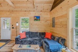 Ein Holzblockhaus-Interieur mit einem großen Ecksofa, einem Couchtisch und einem Bild an der Wand.