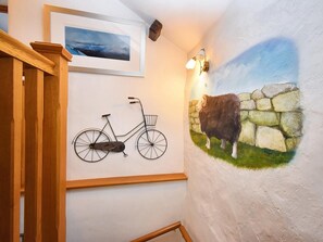 A staircase with a wooden handrail, a wall-mounted bicycle, and a mural of a cow. - 3 Bed in Keswick (oc-94346) (Threlkeld)