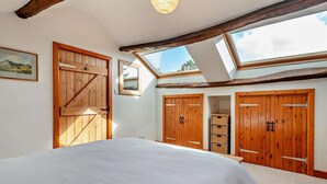 A bedroom with a large bed, wooden wardrobes, a skylight, and a framed picture on the wall. - 3 Bed in Keswick (oc-94346) (Threlkeld)