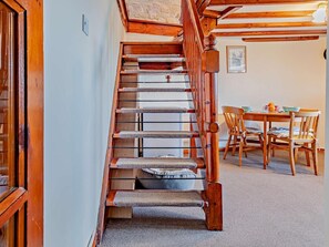 Un escalier en bois avec un arbre à chat, une table à manger avec des chaises et un tableau encadré au mur.