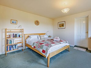 Ein Schlafzimmer mit einem Bett, einem Bücherregal, einer Tür und einer Wandleuchte.