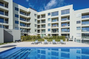 Ein modernes Hotel mit Schwimmbad, mehreren Balkonen und einer gepflegten Außenanlage.