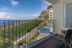 Un balcon donnant sur une piscine, avec une chaise et une table.