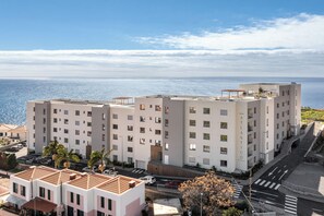 Ein mehrstöckiges Hotel mit Blick auf das Meer, einem Parkplatz und einer Fußgängerzone.