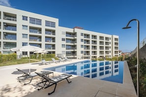 Un hôtel moderne doté d’une piscine, de chaises longues et de parasols.