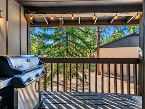 Ein Grill auf einem Balkon mit Blick auf Bäume und ein Haus.