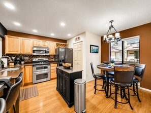 A modern kitchen with wooden cabinets, stainless steel appliances, and a dining area with a round table and chairs. - 2BR mountain condo w fireplace, board games! (Pinetop)