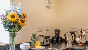 Eine Küche mit Kaffeemaschine, Toaster, Wasserkocher und einer Vase mit Blumen.