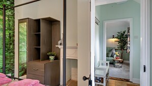 Un dormitorio con cama, armario, espejo y vista a un bosque por la ventana.