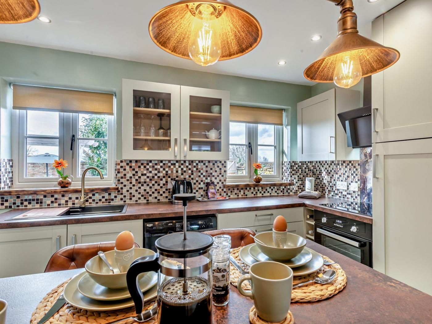 Una cocina moderna con una isla central, armarios empotrados y un ventanal con vistas a un jardín.