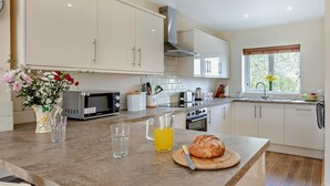 A modern kitchen with white cabinets, a microwave, a toaster, and a large window. - 1 Bed in Bridgwater (oc-79215) (Ashcott)