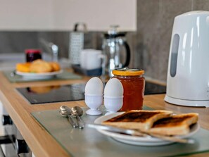 A breakfast setup with toast, eggs, jam, and a kettle on a kitchen counter. - 1 Bed in Woolacombe (oc-76348) (Woolacombe)
