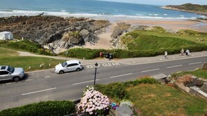Una carretera costera con una clara señal de 'KEEP CLEAR', un litoral rocoso y una playa al fondo.