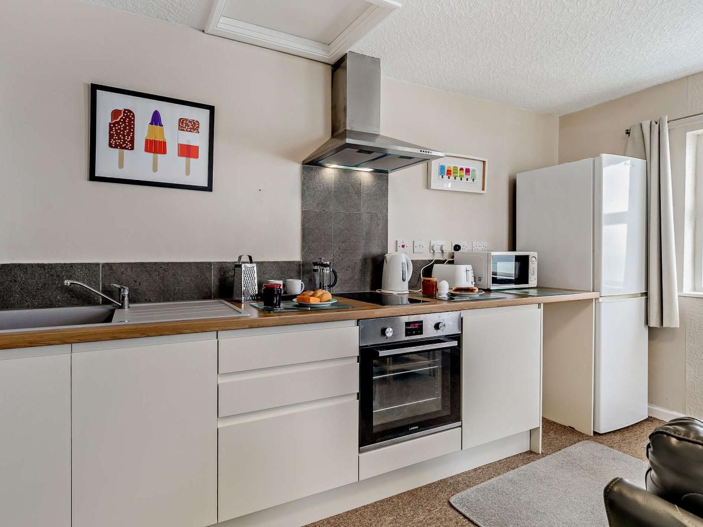 A modern kitchen with a built-in oven, a microwave, and a refrigerator.