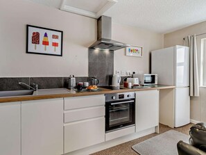 A modern kitchen with a built-in oven, a microwave, and a refrigerator. - 1 Bed in Woolacombe (oc-76348) (Woolacombe)