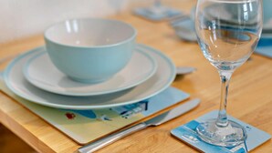 Un tavolo da pranzo con un bicchiere da vino in vetro trasparente, una ciotola azzurra e piatti abbinati.