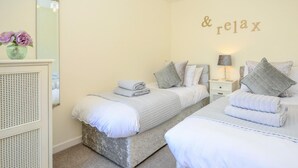 Ein Schlafzimmer mit zwei Betten, einem Schminktisch, einem Spiegel und einem Schild an der Wand mit der Aufschrift '& relax'.