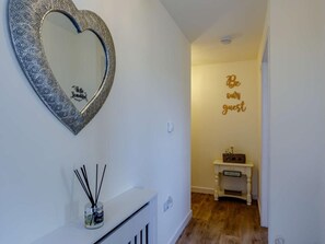 A hallway with a heart-shaped mirror, a small console table with a sign, and a 'Be our guest' sign on the wall. - 2 Bed in Holsworthy (oc-82744) (Pancrasweek)