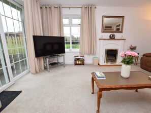 A living room with a television, fireplace, and a coffee table with books. - 2 Bed in Pembroke (oc-47640) (Pembroke)