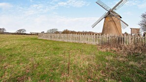 Eine Windmühle in einem grasbewachsenen Feld mit einem Holenzaun.