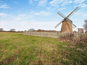 A windmill in a grassy field with a wooden fence. - 1 Bed in Bembridge (oc-94355) (Bembridge)