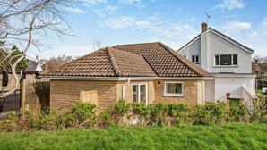 Ein zweistöckiges Haus mit Ziegeldach, einer kleinen angebauten Garage und einem gepflegten Rasen.