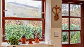 A kitchen with a sink, a window with a view of greenery, and a heart-shaped decoration on the wall. - 2 Bed in Berwick -upon- Tweed (oc-cn181) (Spittal)